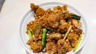 Kanton usulü bol yağda kızartılmış tuz ve biberli kalamarı beyaz tabakta sarımsak ile yakın.