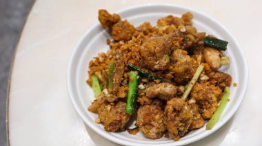 Kanton usulü bol yağda kızartılmış tuz ve biberli kalamarı beyaz tabakta sarımsak ile yakın.