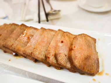 Çin baharatlı soya sosuna yakın beyaz tabakta salamura edilmiş sığır eti dilimi.