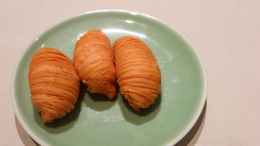 Üç parça Hong Kong usulü Çin usulü, bol yağda kızartılmış, yeşil tabakta parçalanmış şalgam ile birlikte puf böreği. Boşluğu sağda kopyala.