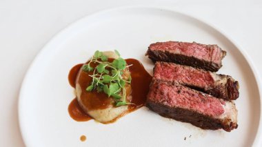 Üç parça az pişmiş biftek ve yanında sos olan patates püresi ve uzay fotokopisi çek.