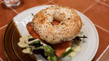 Susam ve balkabağı tohumlu simit, salata, tütsülenmiş somon ve avokado tabağı.