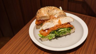 Susam ve balkabağı tohumu simit, lahana, tütsülenmiş somon ve avokado ile iki yarıya bölünmüş tabakta yüzey alanını fotokopi alanı ile gösteriyor.