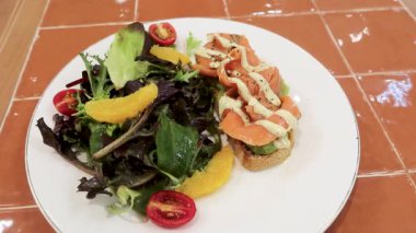 Tütsülenmiş somonlu avokado tostu ve yanında fotokopi alanı olan çeşitli salata.