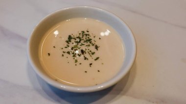Kremalı çorbayı mermer masanın tepesinde bitkilerle kaplayın.