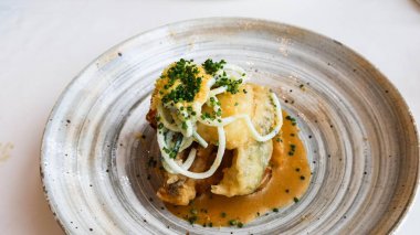 Kızarmış balık filetosunu soğan turşusuyla kaplayın, soğanla süsleyin ve lezzetli bir sosla servis edin, sade gri bir tabakta fotokopi alanı ile sunun.