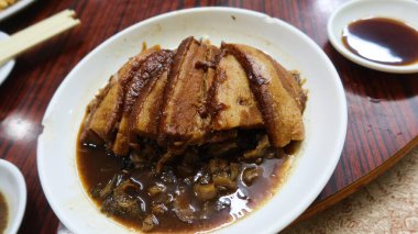 Çin usulü soya sosu, haşlanmış domuz eti, yanında hardal yeşili ve beyaz tabakta sebze.