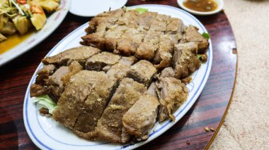 Kanton usulü taro ördeği yakın plan, Taro ile kavrulmuş çıtır ördek, taro kökünden bir battaniyeye sarılmış nemli ördek.