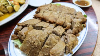 Kanton usulü taro ördeği yakın plan, Taro ile kavrulmuş çıtır ördek, taro kökünden bir battaniyeye sarılmış nemli ördek.