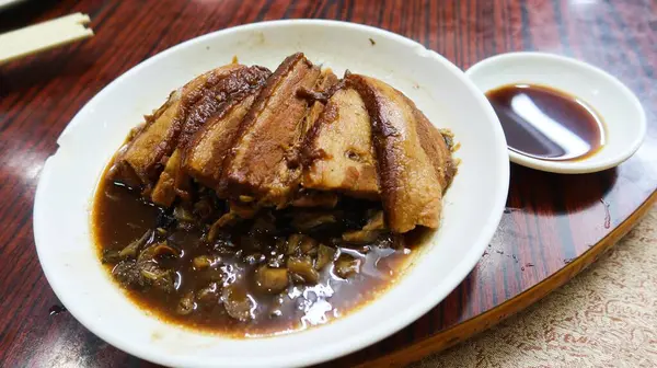 Çin usulü soya sosu, haşlanmış domuz eti, yanında hardal yeşili ve beyaz tabakta sebze.