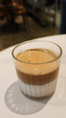 İki katlı, düz beyaz bir kahvenin, kahverengi kahve tabakasının ve beyaz bir bardak sütün fotokopi alanı olan bir bardağın dikey fotoğrafı.