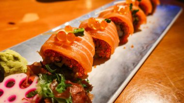 Japon somonlu suşiyi kapatın. Yanında sebzeler olsun. Uzun bir tabakta süslemek için.