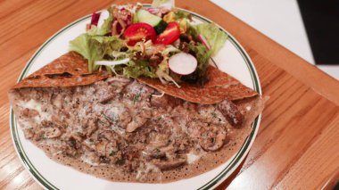 Fransız sığır eti, mantar ve siyah trüf soslu galetelere yakın ahşap bir masada peynir, sağda kopya alanı