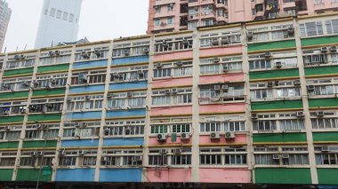 Sha Tsui Yolu, Tsuen Wan, Hong Kong - 2 Ağustos 2025: Renkli pembe, mavi ve yeşil apartman dairesi gündüz vakti pencereli ve klimalı