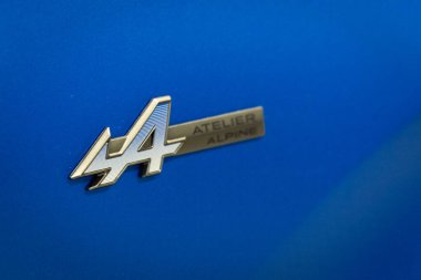 Renault Rafale E-Tech 4x4 Atıcı Alp Rozeti 'nin mavi bir araba üzerindeki yakın çekimi.