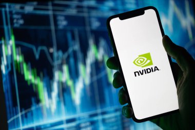 Siluette, Nvidia logosu sergilenen bir el cep telefonu tutuyor. Arkasında, yeşil renklerde vurgulanan yükselen hisse senedi fiyatlarını gösteren bir fon yer alıyor.