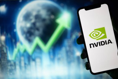 Siluette, Nvidia logosunu gösteren bir el cep telefonu tutuyor. Arka planda, bir ay boyunca yukarı bakan yeşil bir borsa oku var.