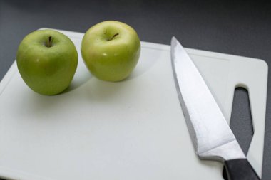Kesme tahtasının üzerinde iki elma ve bir bıçak var.