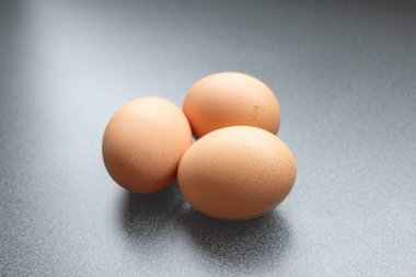 Yukarıdan görünen koyu arkaplanı olan üç yumurta.