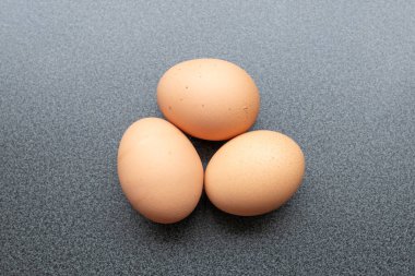 Yukarıdan görünen koyu arkaplanı olan üç yumurta.