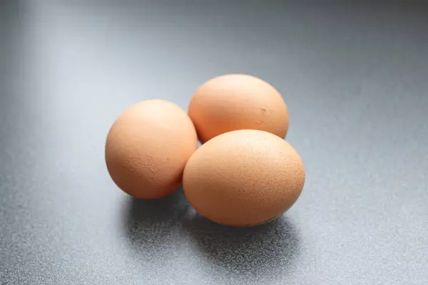 Yukarıdan görünen koyu arkaplanı olan üç yumurta.