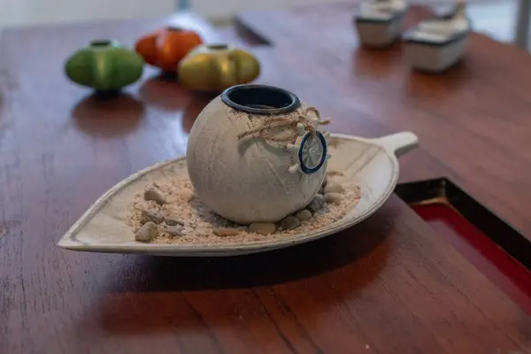 Koyu ahşap bir masada deniz temalı dekorasyonların yakın çekimi ve pencereden gelen güneş ışığı