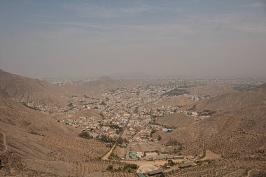 Açık ve güneşli bir günde Peru 'nun ıssız dağlarının ortasındaki kuru nüfuslu bir vadi şehrinin havadan görünüşü.
