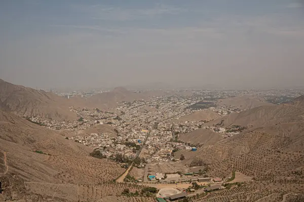 Açık ve güneşli bir günde Peru 'nun ıssız dağlarının ortasındaki kuru nüfuslu bir vadi şehrinin havadan görünüşü.