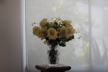 Beyaz gül buketi cam bir vazoda bulanık beyaz kürtatin arka planda