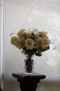 Beyaz gül buketi cam bir vazoda bulanık beyaz kürtatin arka planda