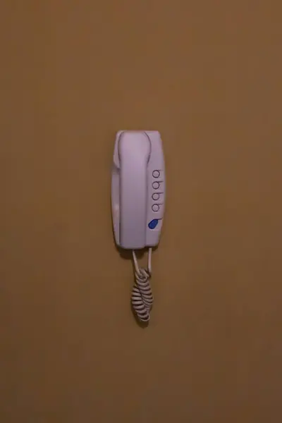 White cable phone on mustard yellow wall