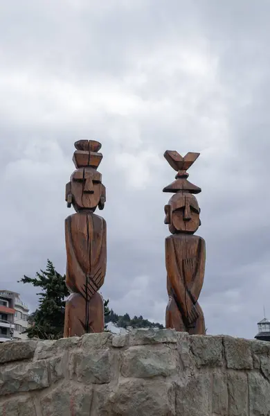 Two wooden Nahuel Huapi Totems on top of a rocky wall