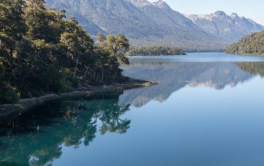 Yoğun ormanlarla dolu sakin ve rahatlatıcı dağ sırasının yatay görüntüsü gölün durgun su duvar kağıdına yansıyor.