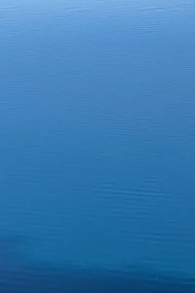 Küçük dalgaların rahatlatıcı arka planı ve canlı mavi suyun dalgaları