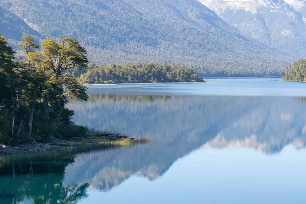 Yoğun ormanlarla dolu sakin ve rahatlatıcı dağ sırasının yatay görüntüsü gölün durgun su duvar kağıdına yansıyor.