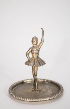 Paslı, parlak, gümüş balerin figürü. Altında beyaz bir plaka var.