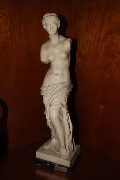 Klasik Yunan çıplak Venus de Milo heykeli (Venere di Milo) seramik heykel yapısı koyu ahşap arka planda