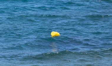 Sakin suda yüzen izole edilmiş sarı şişenin yatay görüntüsü