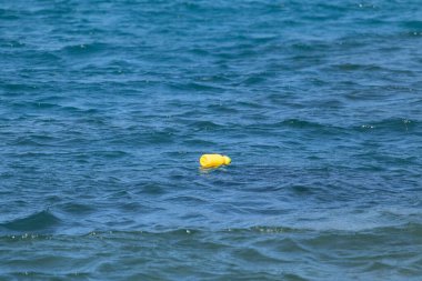 Sakin suda yüzen izole edilmiş sarı şişenin yatay görüntüsü