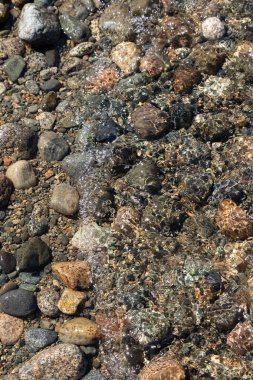 Toprak zeminde kumla kaplı birçok kaya ve çakıl taşı.