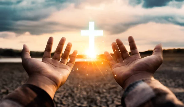 Man hand pray with cross for protecting environment from water crisis and the impact of climate change, social responsibility and save water, drought disaster relief and water demand concept.
