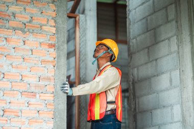 İnşaat işçisi yapının her parçasının uyduğundan emin olmak için inşaat standartlarını denetliyor..