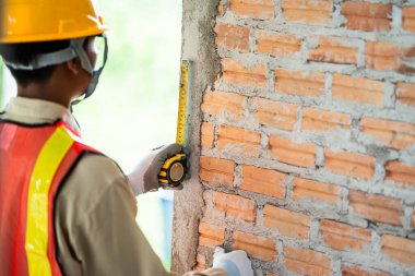 Elinde mezura tutan bir mühendis bina inşaat standartlarını inceliyor.