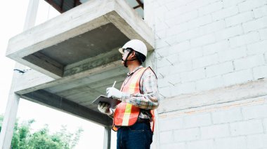 İnşaat işçisi inşaat alanını inceliyor..