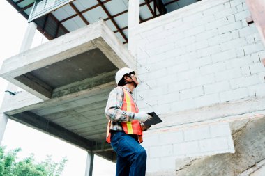 İnşaat işçisi inşaat alanını inceliyor..