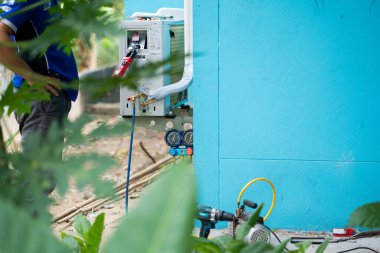 Uzaktan kumandalı ekipman üzerinde çalışan teknisyen endüstriyel bakım yeşil çevre yakın çekim operasyonel verimlilik