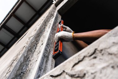 İnşaat işçisi inşaat sahasında düzey araç kullanıyor. Şehir ortamının yakın çekim hassasiyeti bina inşaatında