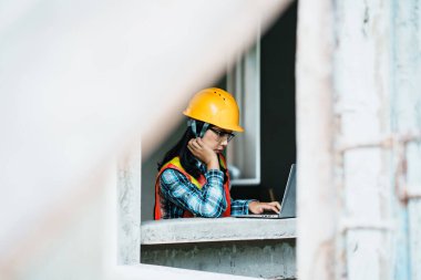 İnşaat işçisi, inşaat alanında dizüstü bilgisayar kullanıyor. Modern çalışma alanı, kapalı alan odaklı perspektif.