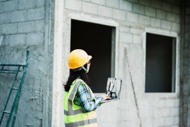 İnşaat işçisi inşaat alanında dizüstü bilgisayar kullanarak proje yönetimi için profesyonel bakış açısı çekti
