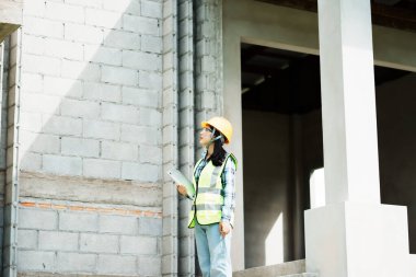 İnşaat işçisi kentsel gelişim alanını inceliyor. Gündüz fotoğrafı, yakın plan güvenlik ve uyum odaklı.